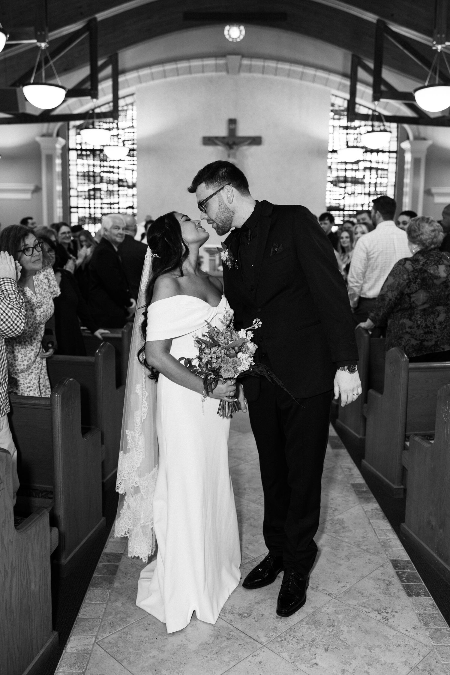 Bride and groom share a kiss to end their church ceremony surrounded by their closest friends and family.