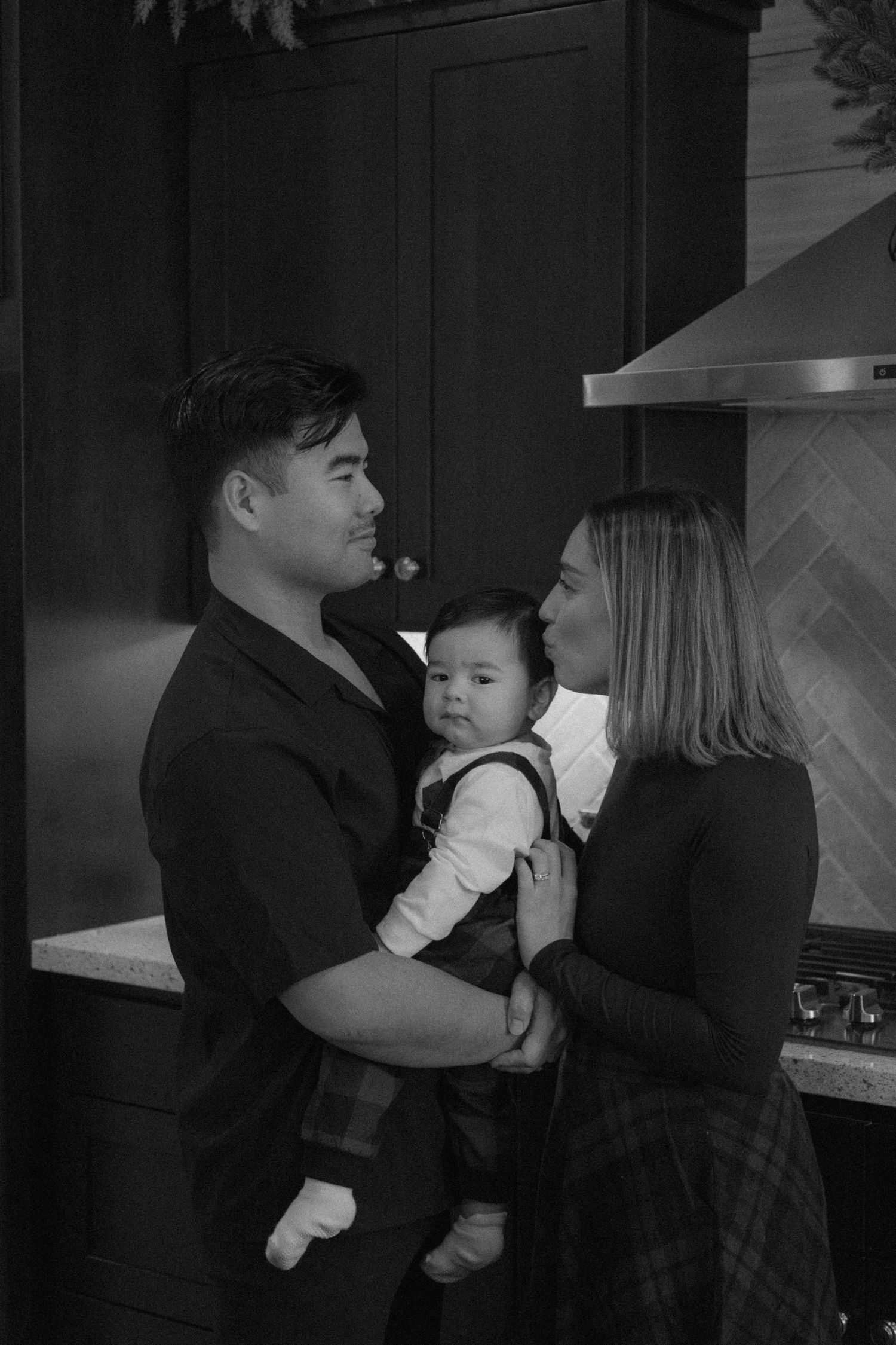 A black and white photo sequence shows a baby being held and kissed in a dimly lit room.