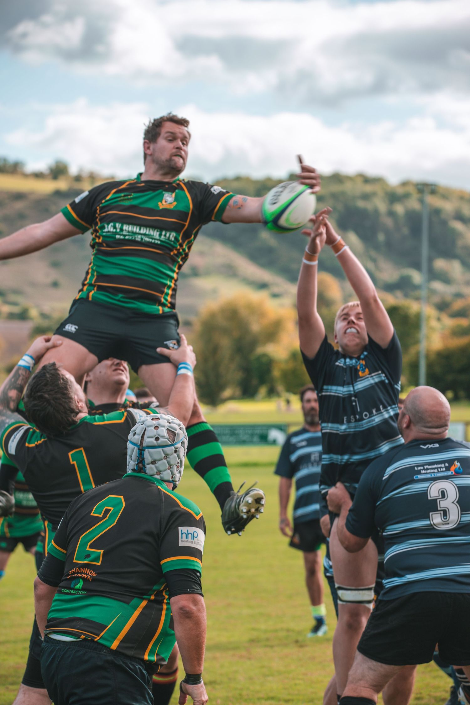 Rugby players competing in a line-out play during an intense match on a grassy field.