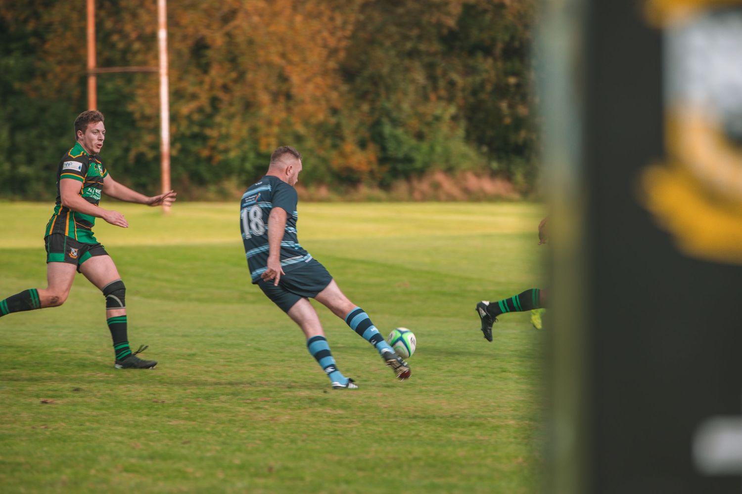 Action shot of rugby players competing for possession during a match on autumn field.