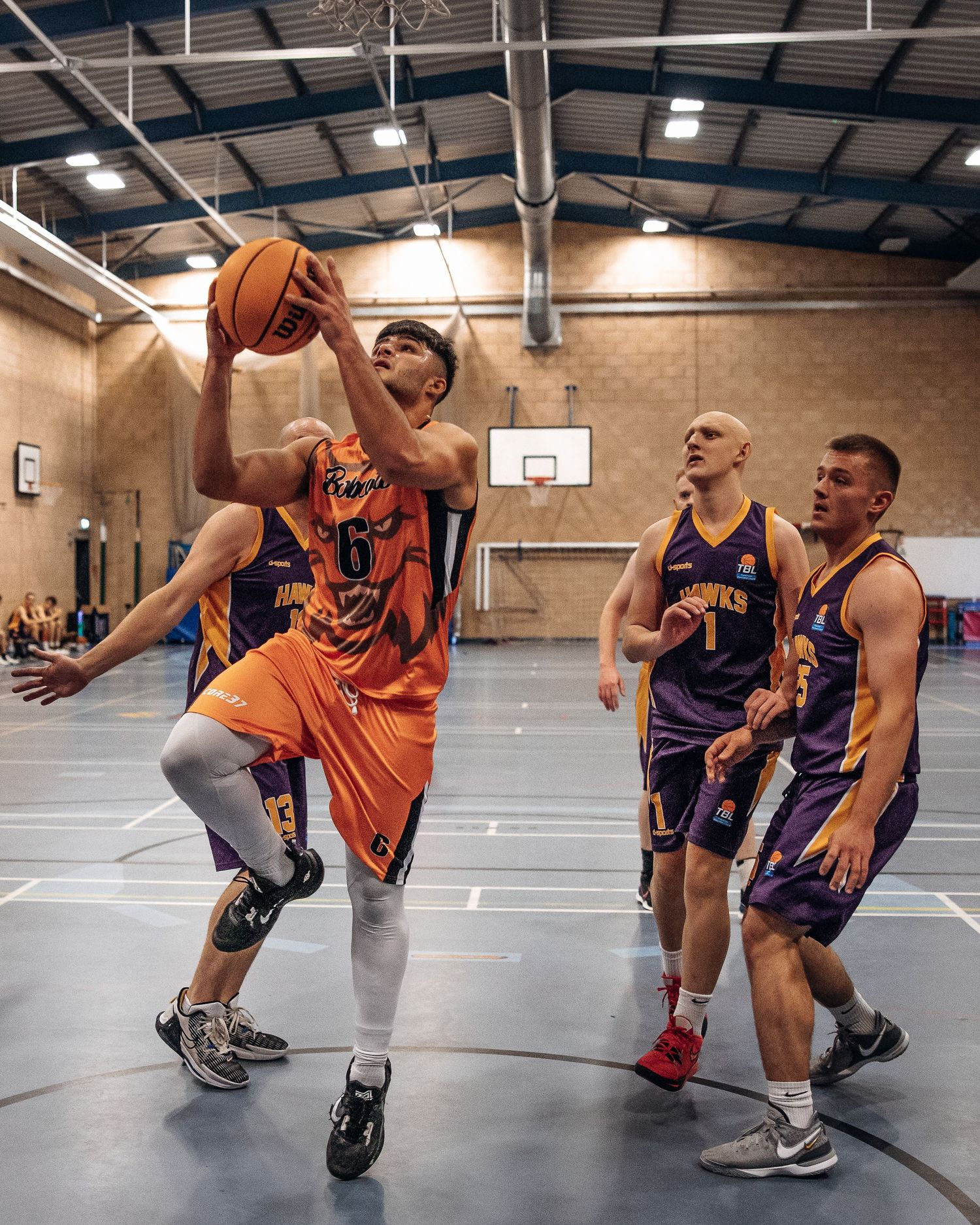 Players compete intensely for position during indoor basketball game.