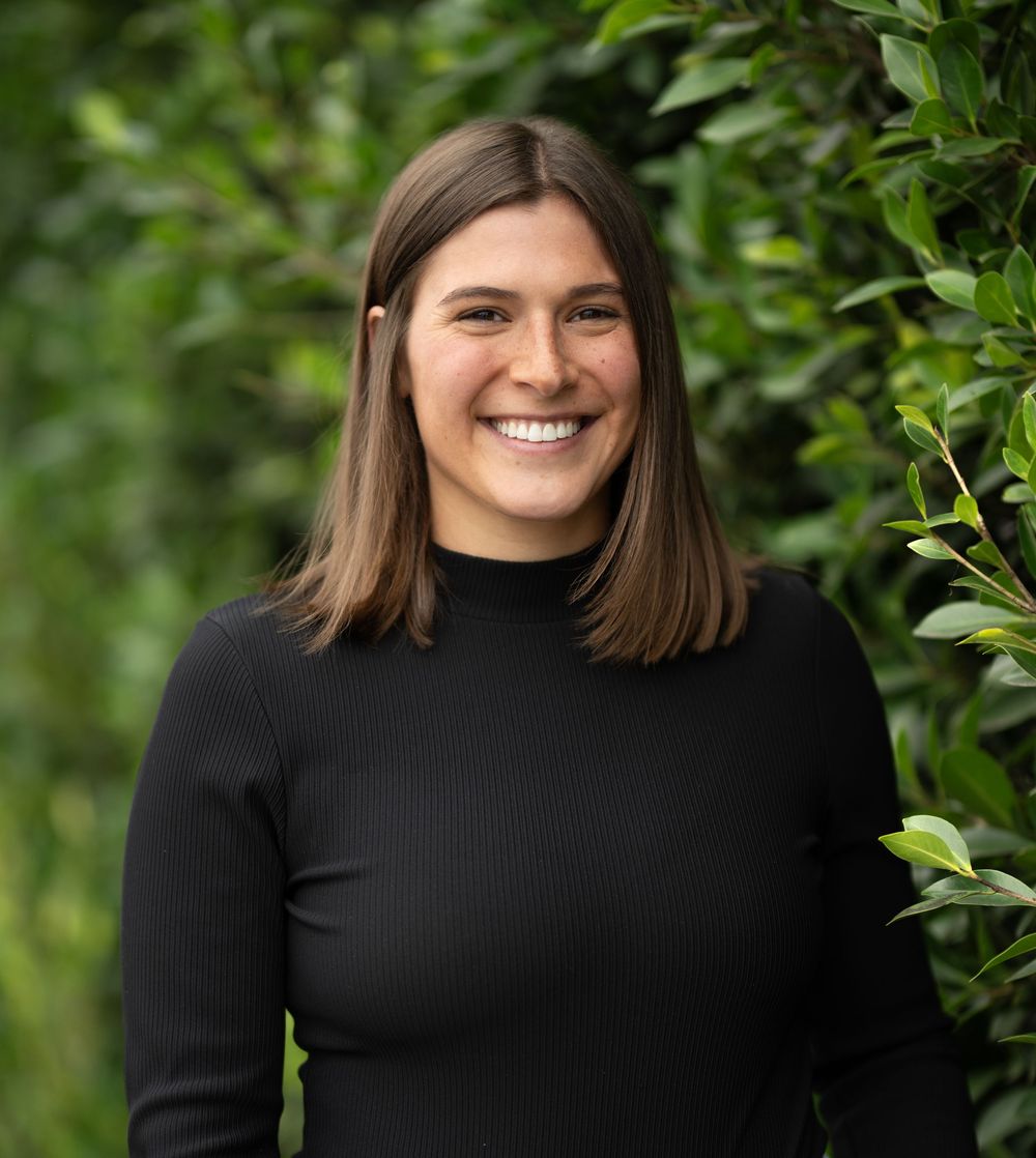 A series of five portrait photos of a person in a black sweater against a green leafy background.