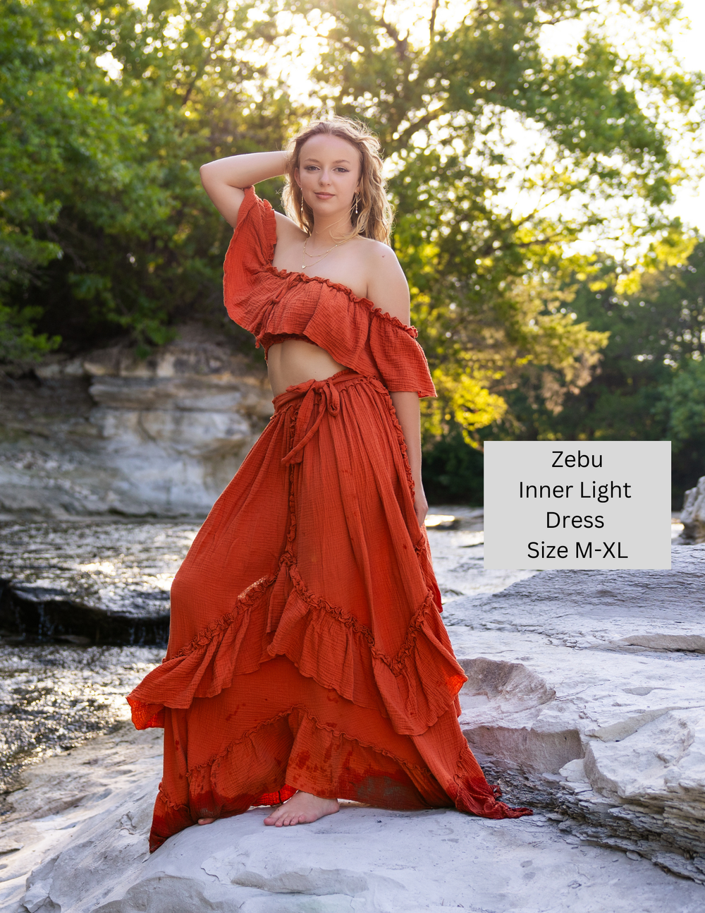 Blonde haired girl near water wearing Zebu dress inner light in orange.