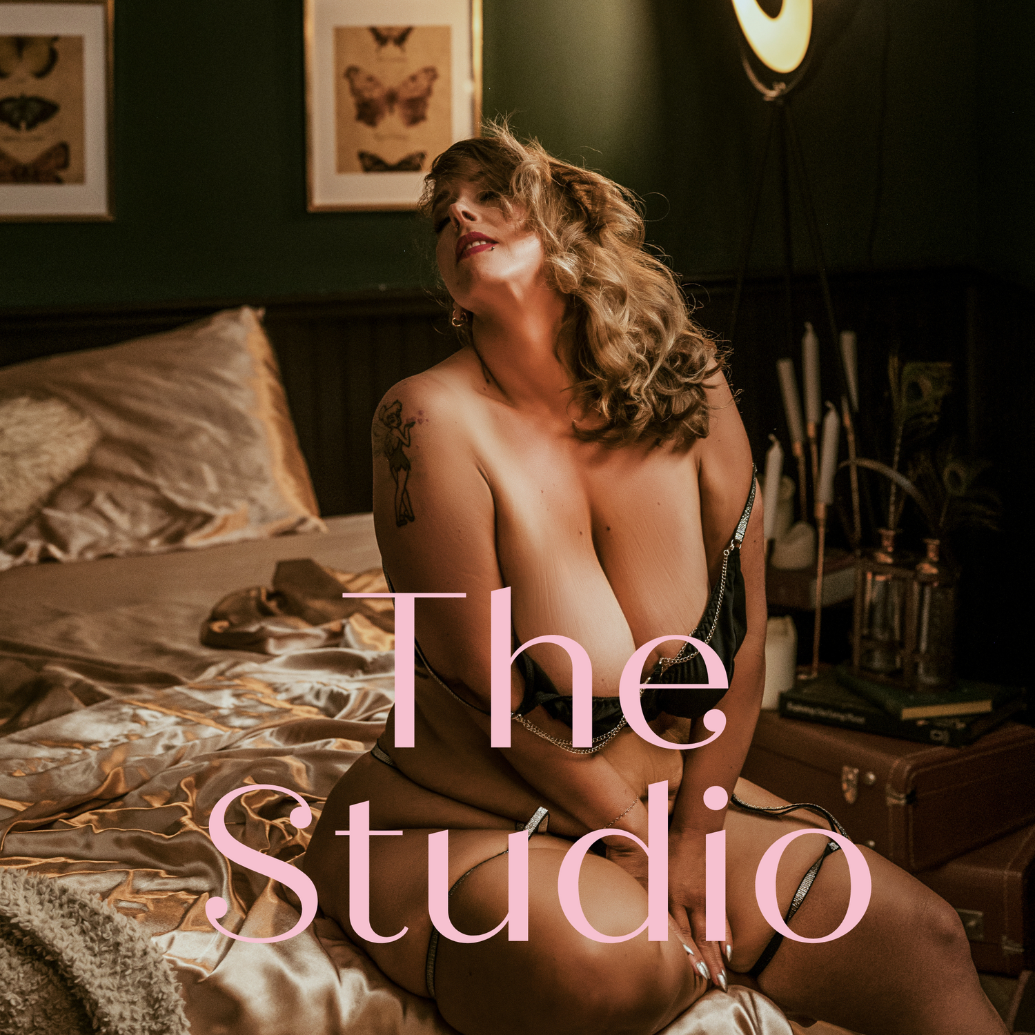Vintage boudoir photography setup in dark room with framed butterfly art on wall and moody lighting.