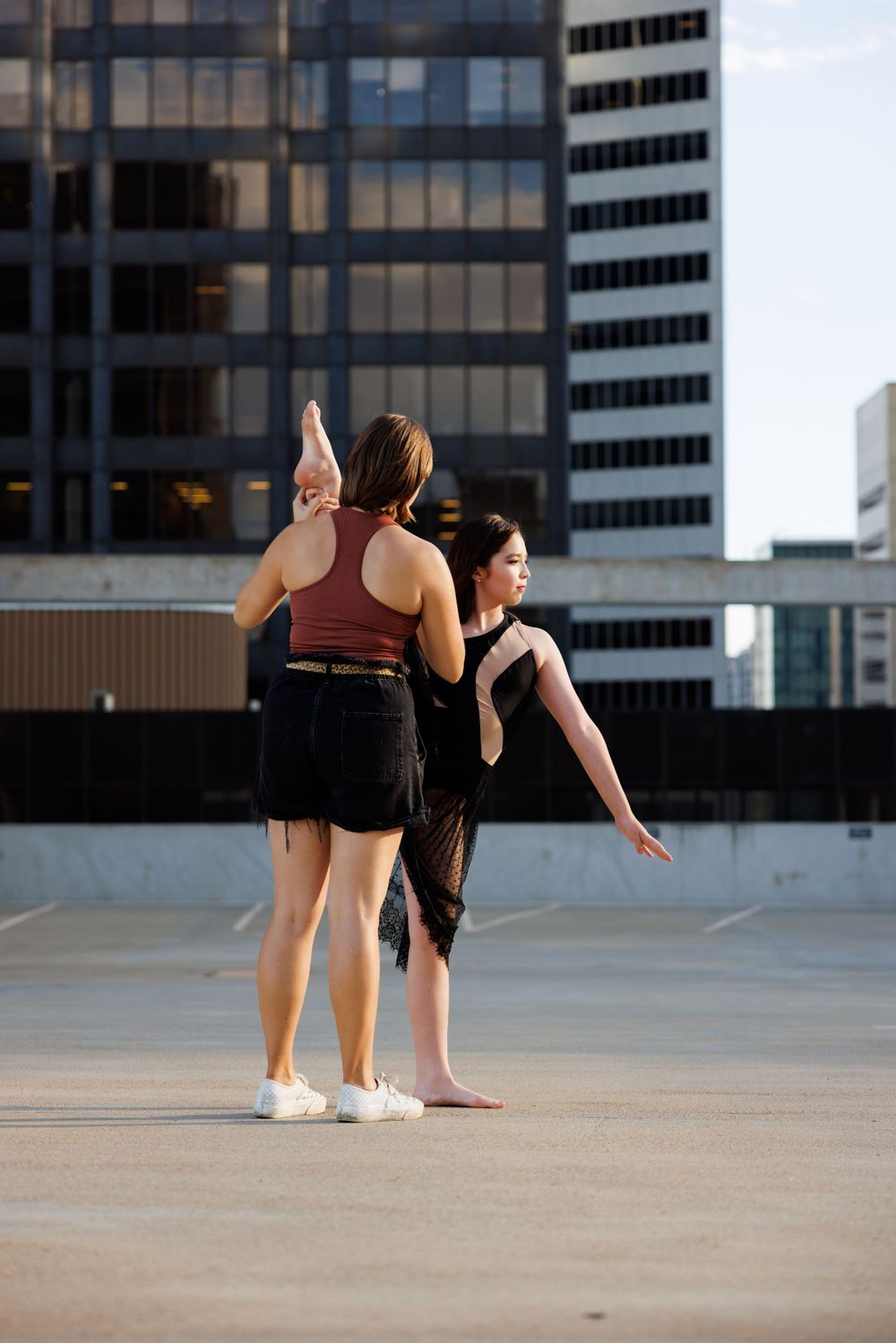 Two dancers practicing their routine on an urban rooftop with city buildings in background.
