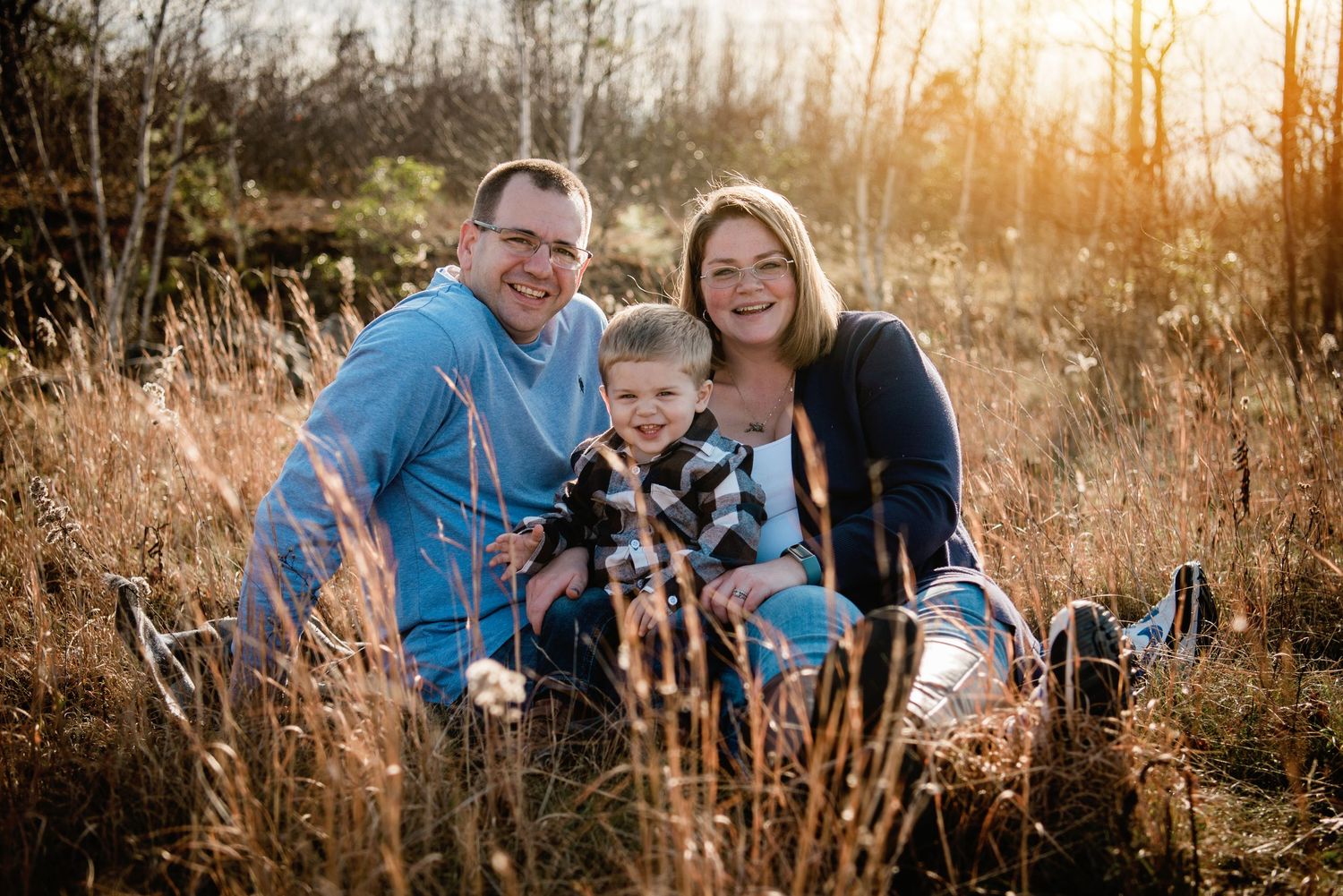 Candid family portraits in a field during golden hour with natural expressions.