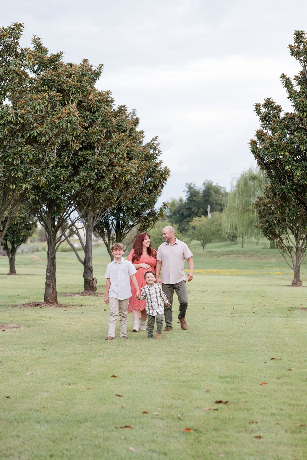 A group walking together on a grassy lawn with trees scattered in the background on an overcast day.