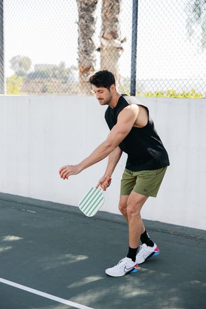 Person demonstrating proper squat form on outdoor exercise court.