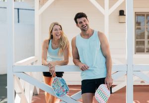 Couple in light blue outfits smiling and relaxing together on a white porch swing.