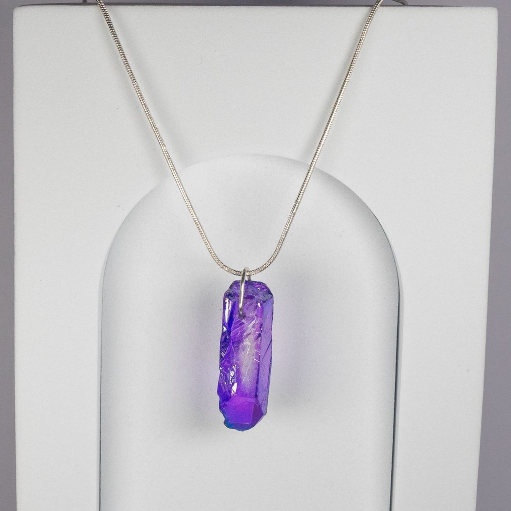 Purple crystal quartz pendant necklace on silver chain against white background.
