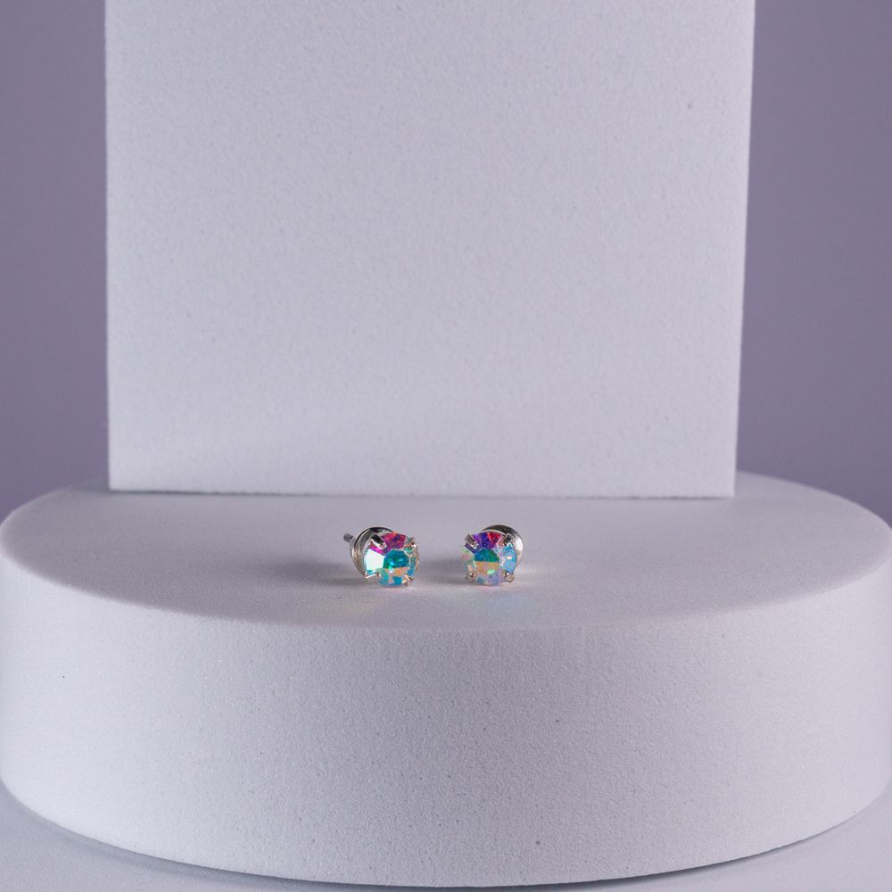 Stud earrings are displayed on a white circular platform.