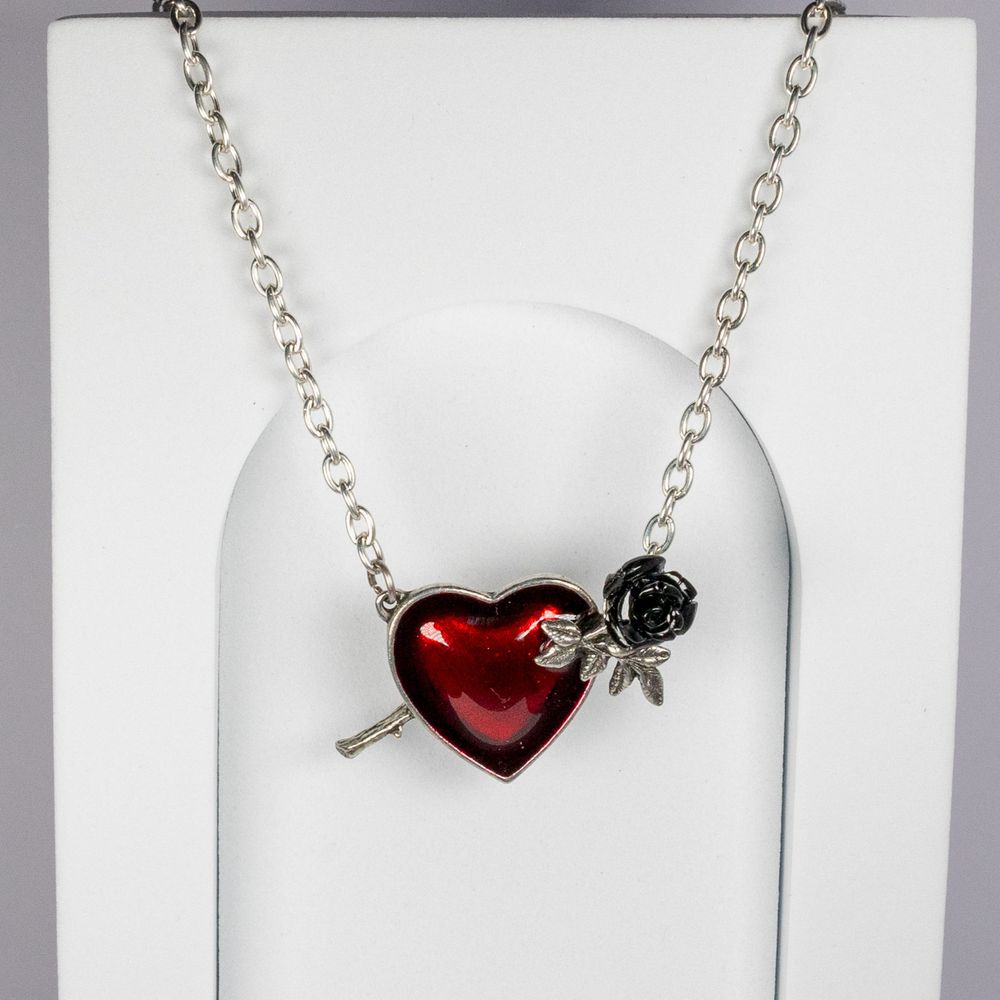 Silver necklace with red heart charm and black rose accent on white display.