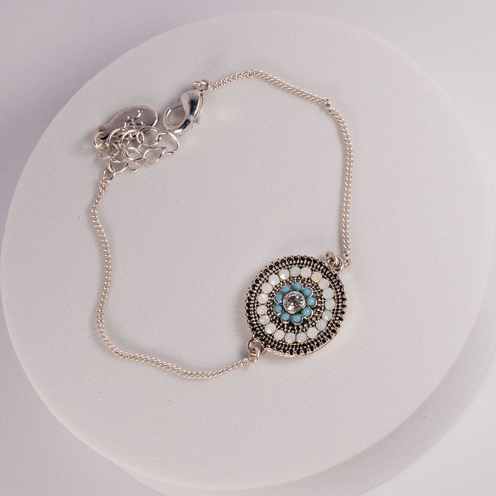 Vintage-style silver necklace with turquoise stone and ornate circular pendant.