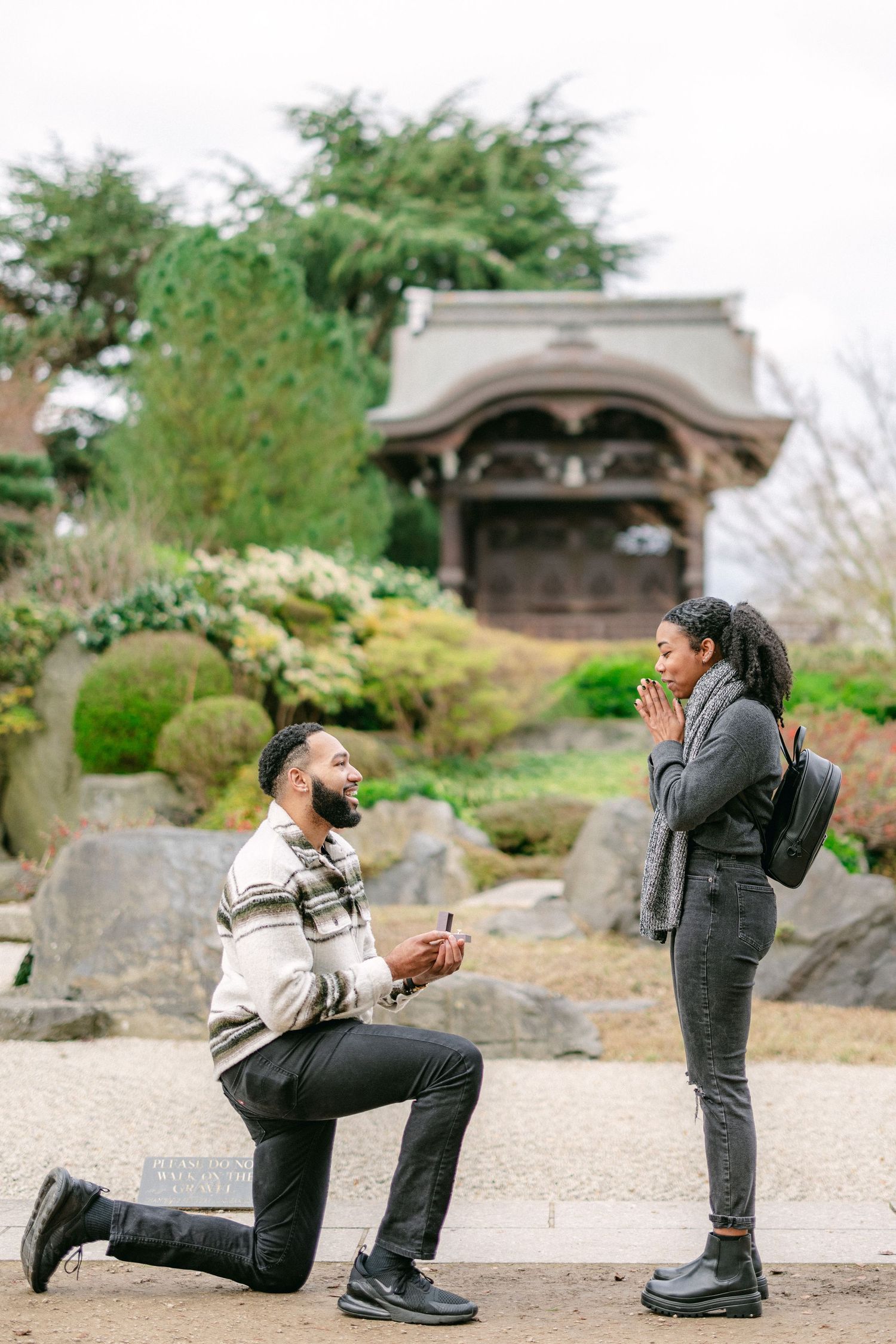 Proposal moment captured in a Japanese garden with traditional architecture in the background.