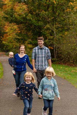 Family walking together on path surrounded by colorful autumn foliage.