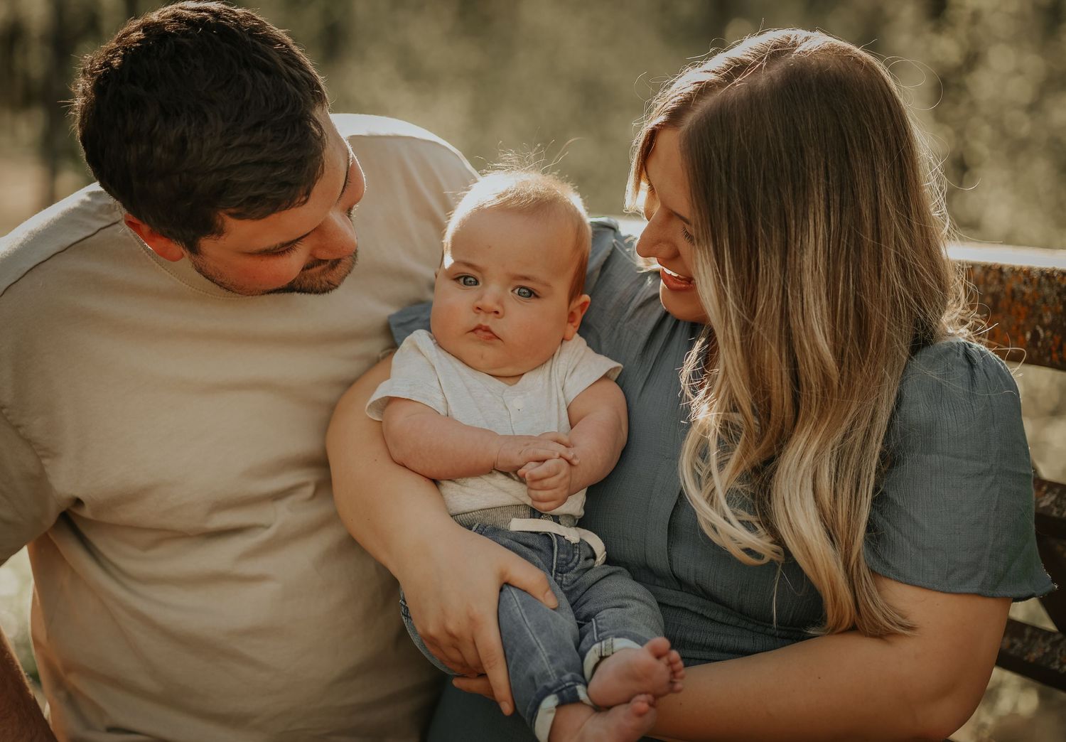 A tender family moment captured in warm lighting as they cuddle together on a sunny day.