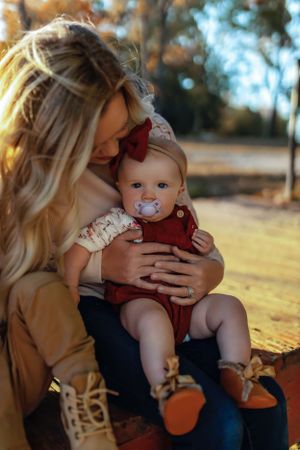 Mother and baby share an intimate moment outdoors during golden hour autumn setting.