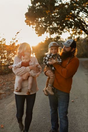 Parents walking with their children on an autumn path during sunset.