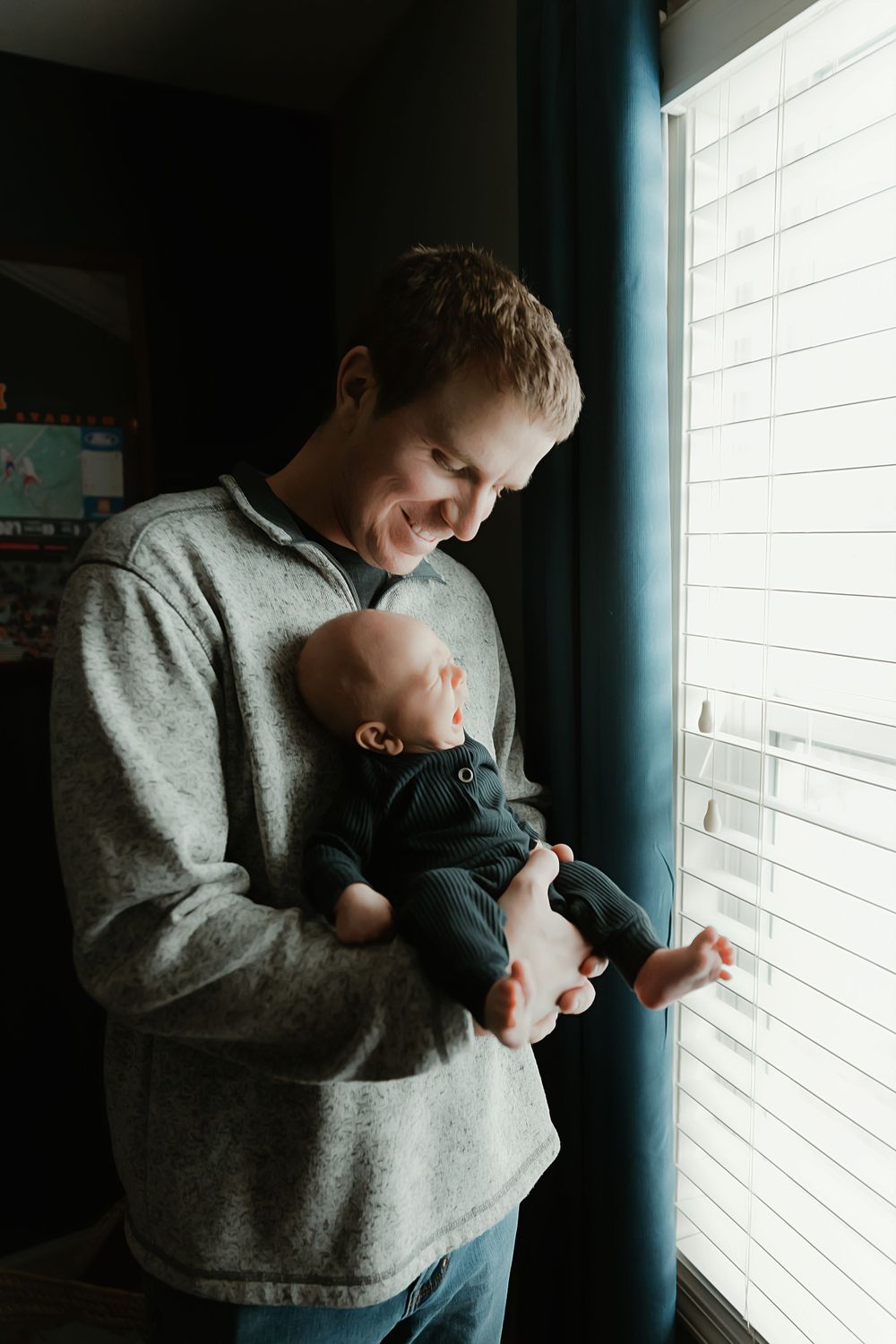 A tender moment between parent and baby while standing by a window with natural light streaming in.