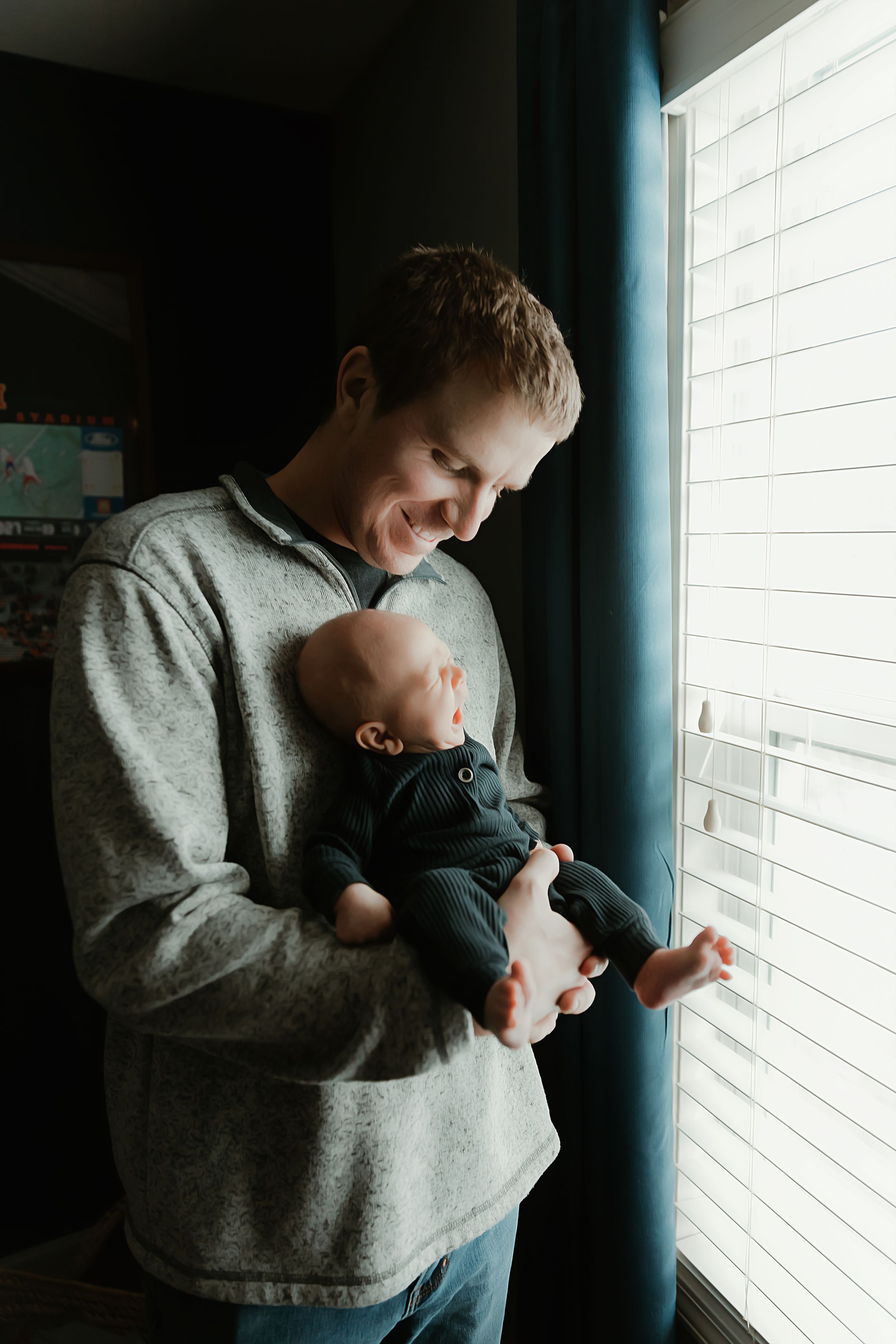 A tender moment between parent and baby while standing by a window with natural light streaming in.