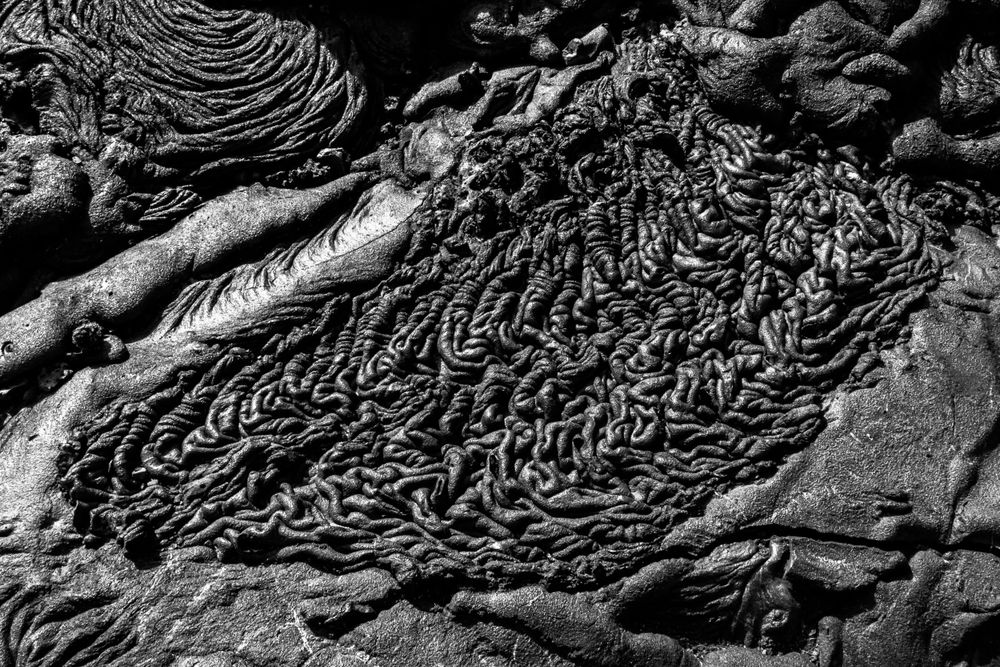 Abstract black and white patterns formed by lava rock formations create dramatic textures and lines.