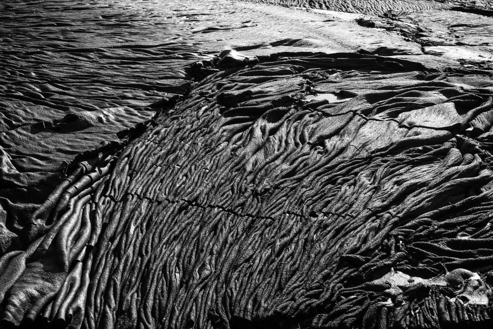 Aerial view of natural rock patterns creating flowing black and white textures.