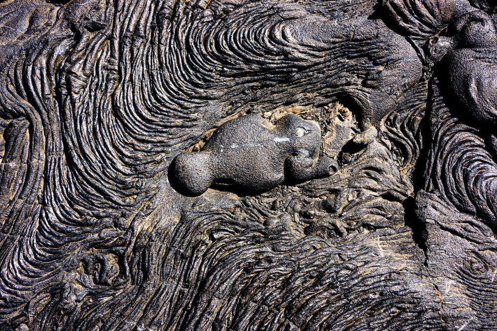 Close-up of intricate swirling patterns in volcanic rock with textured surface detail.