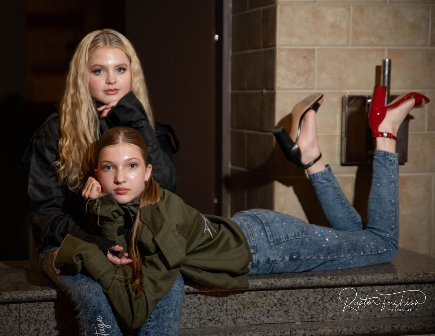 Two models pose artistically against stone wall in casual fashion photoshoot.