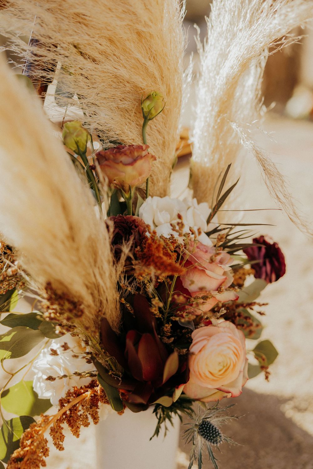 Artistically arranged dried pampas grass and pink roses in a bohemian-style wedding decoration.