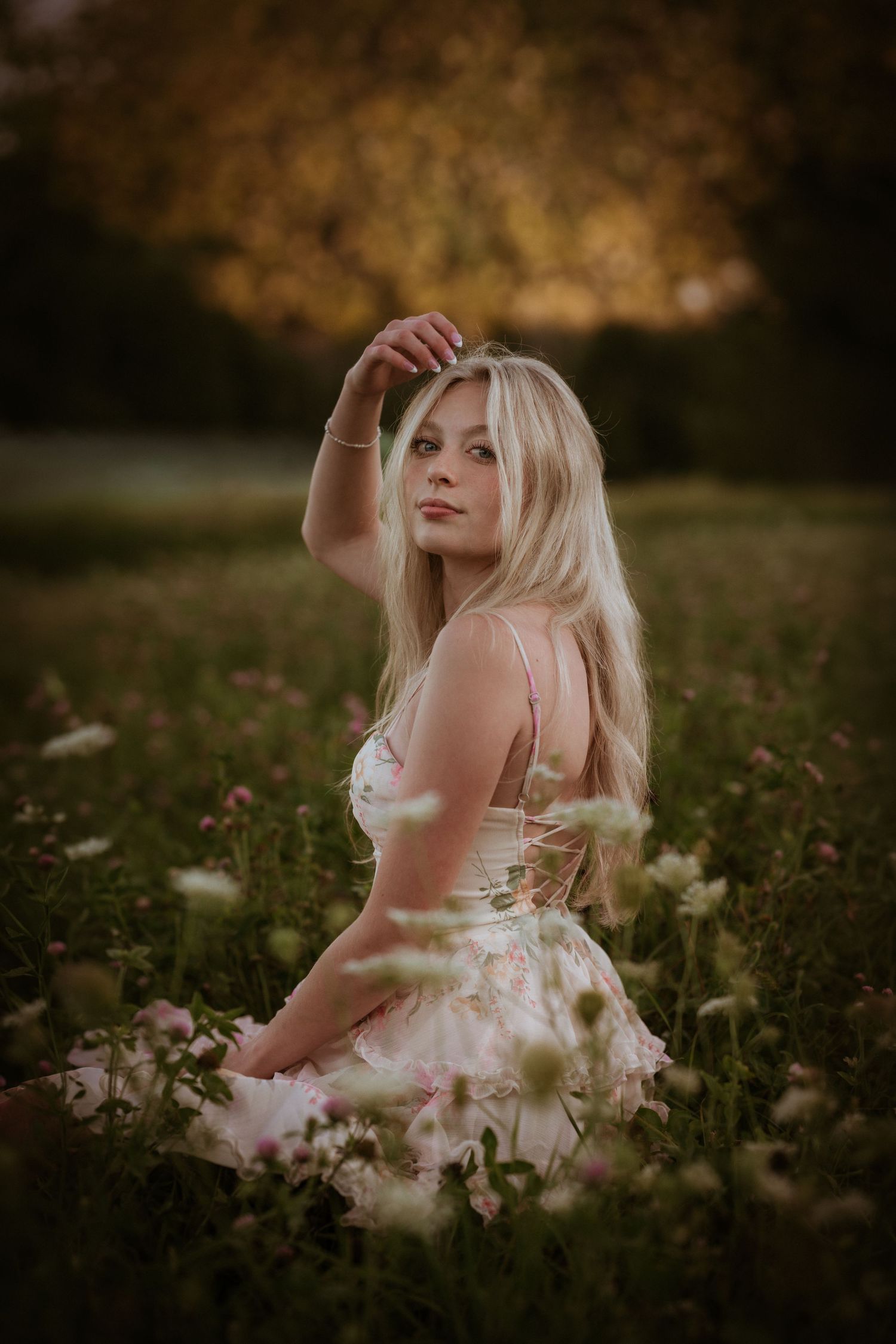 Young blonde woman with green eyes poses among yellow autumn foliage in a natural outdoor portrait.