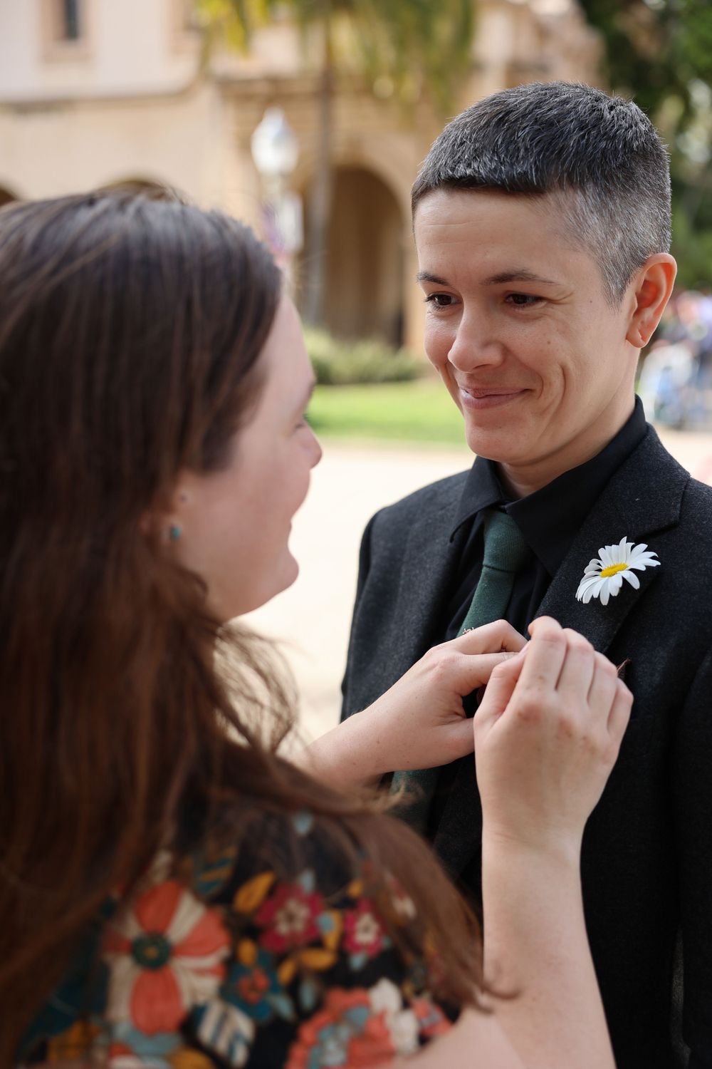 A couple in formal wear sharing an intimate moment outdoors.