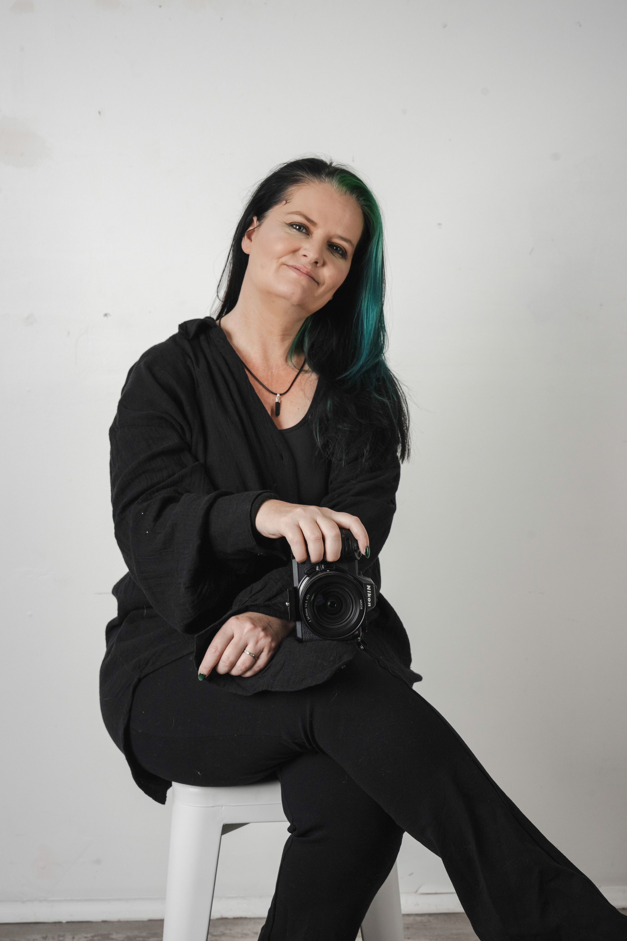 Portrait series showing someone wearing a black sleeveless top against a dark background with ivy.