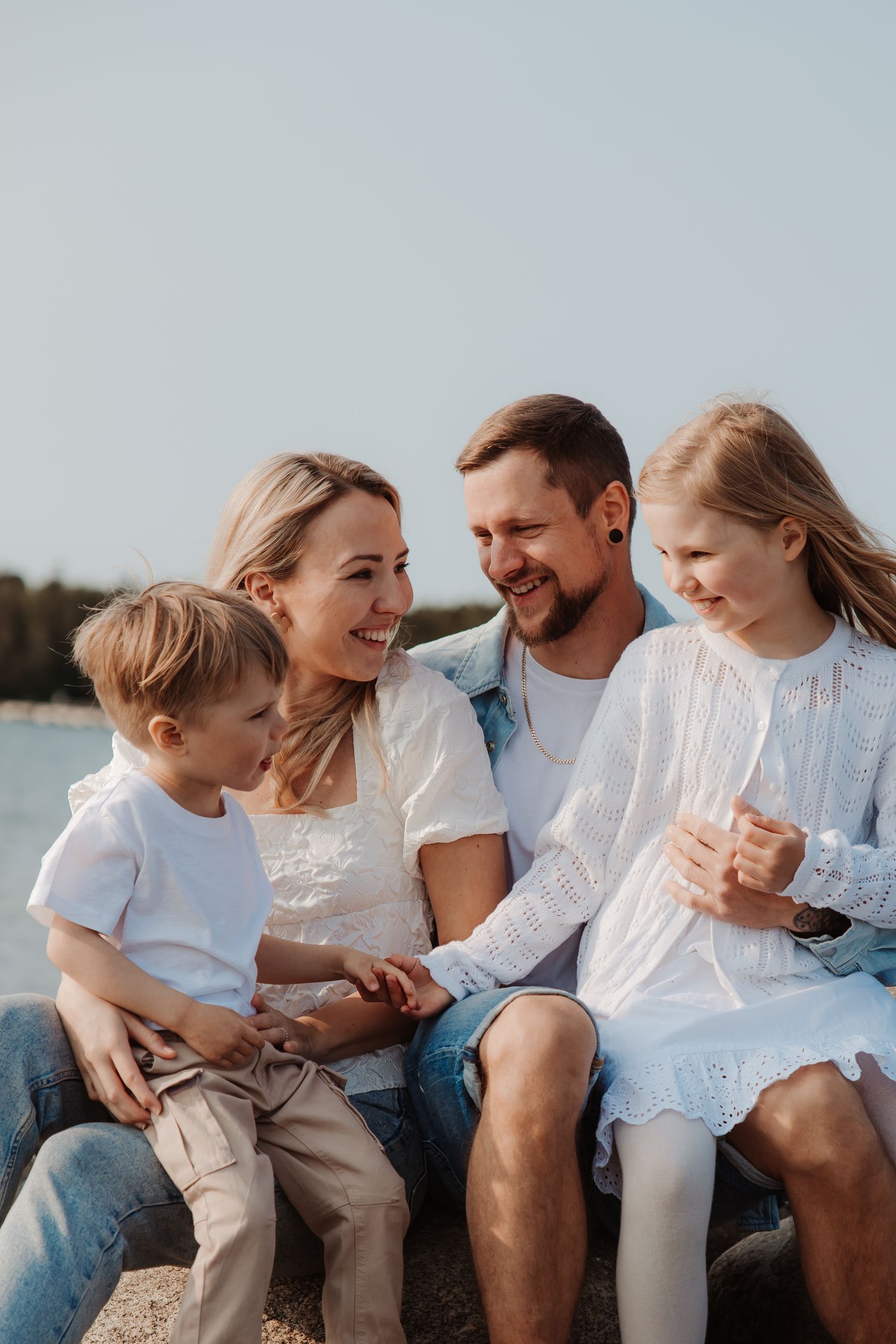 Family sitting together on a beach sharing joyful moments at sunset.