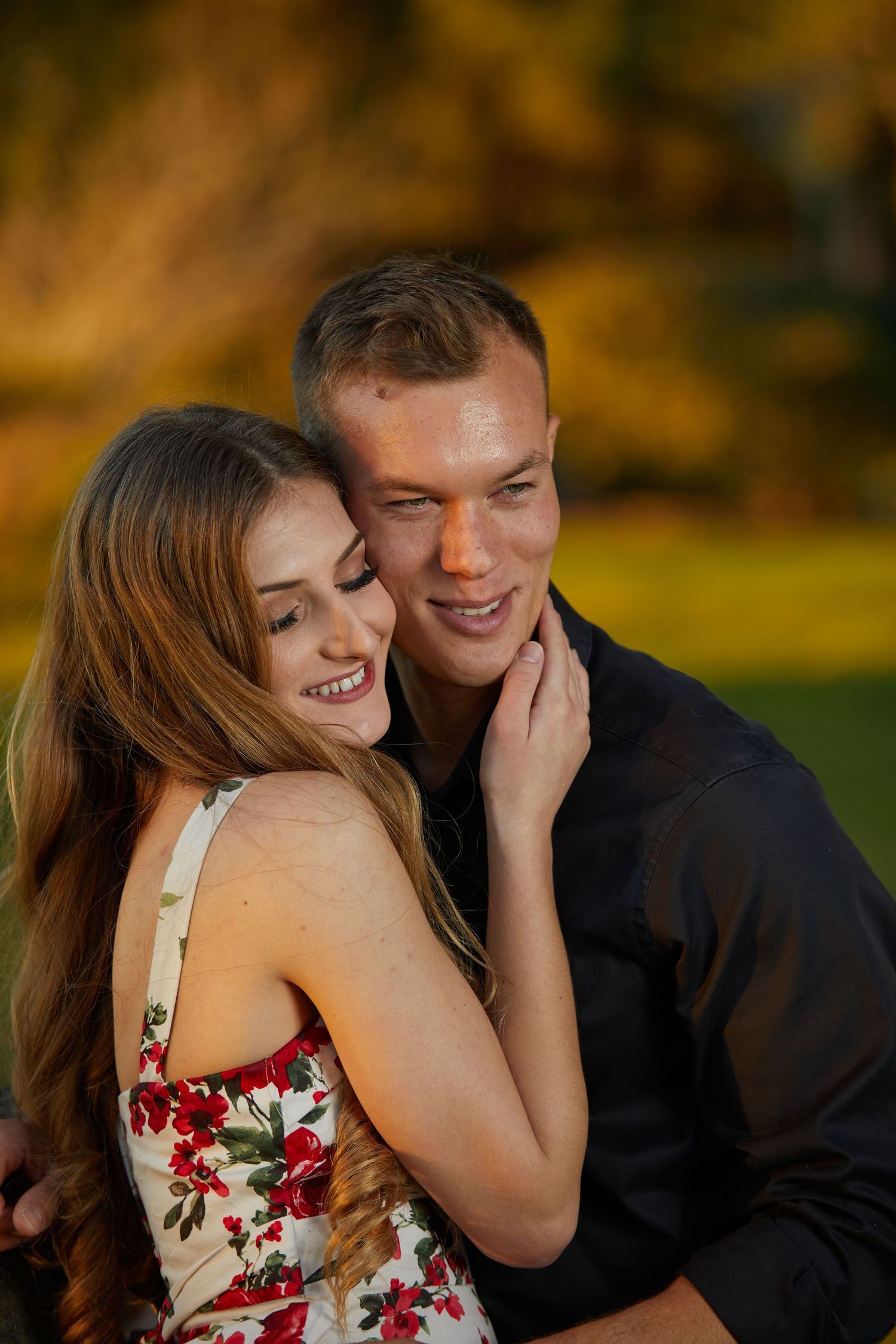 Candid portrait of couple laughing together against warm autumn background.