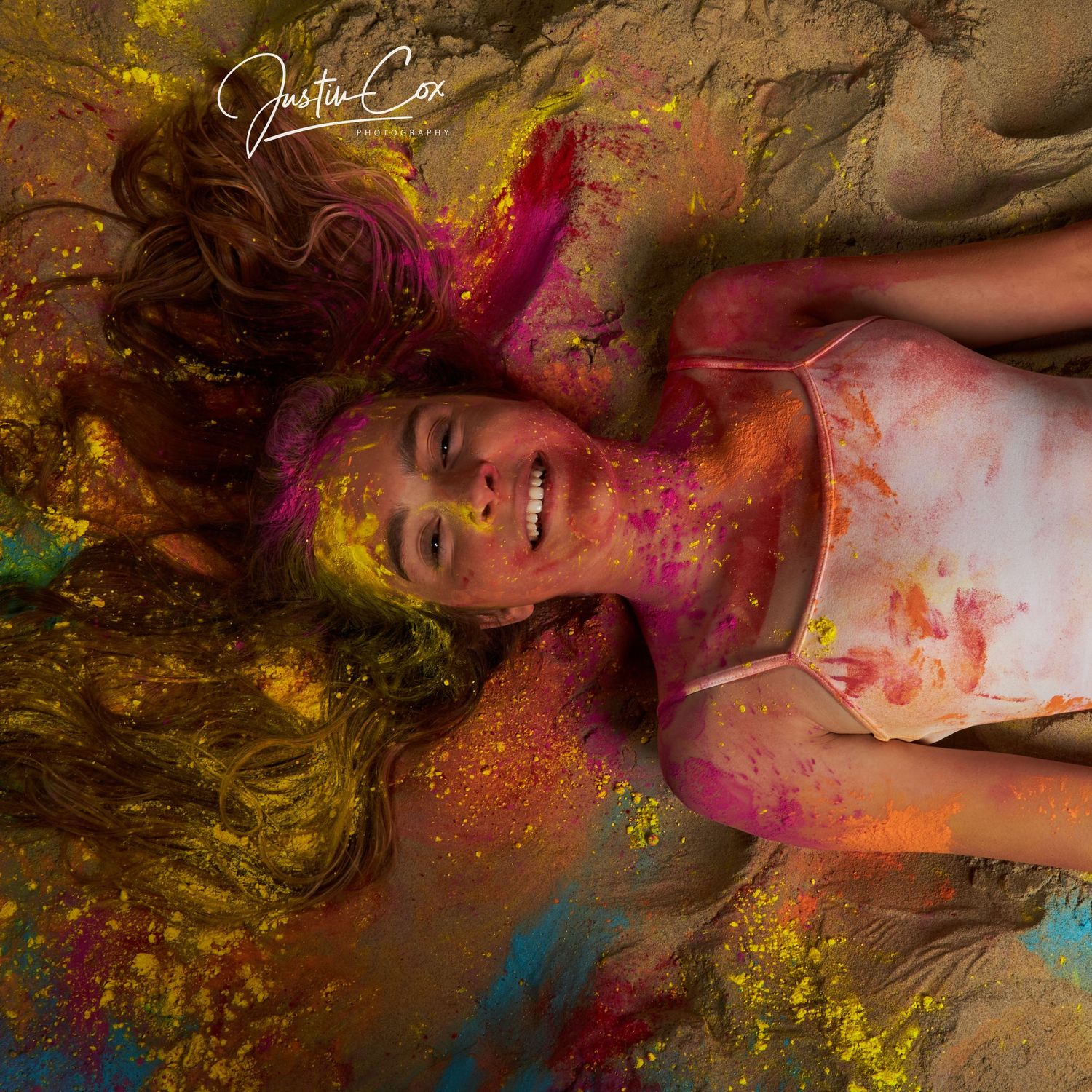 Creative portrait with vibrant powder colors creating dreamy effect on ground with yellow and pink hues.