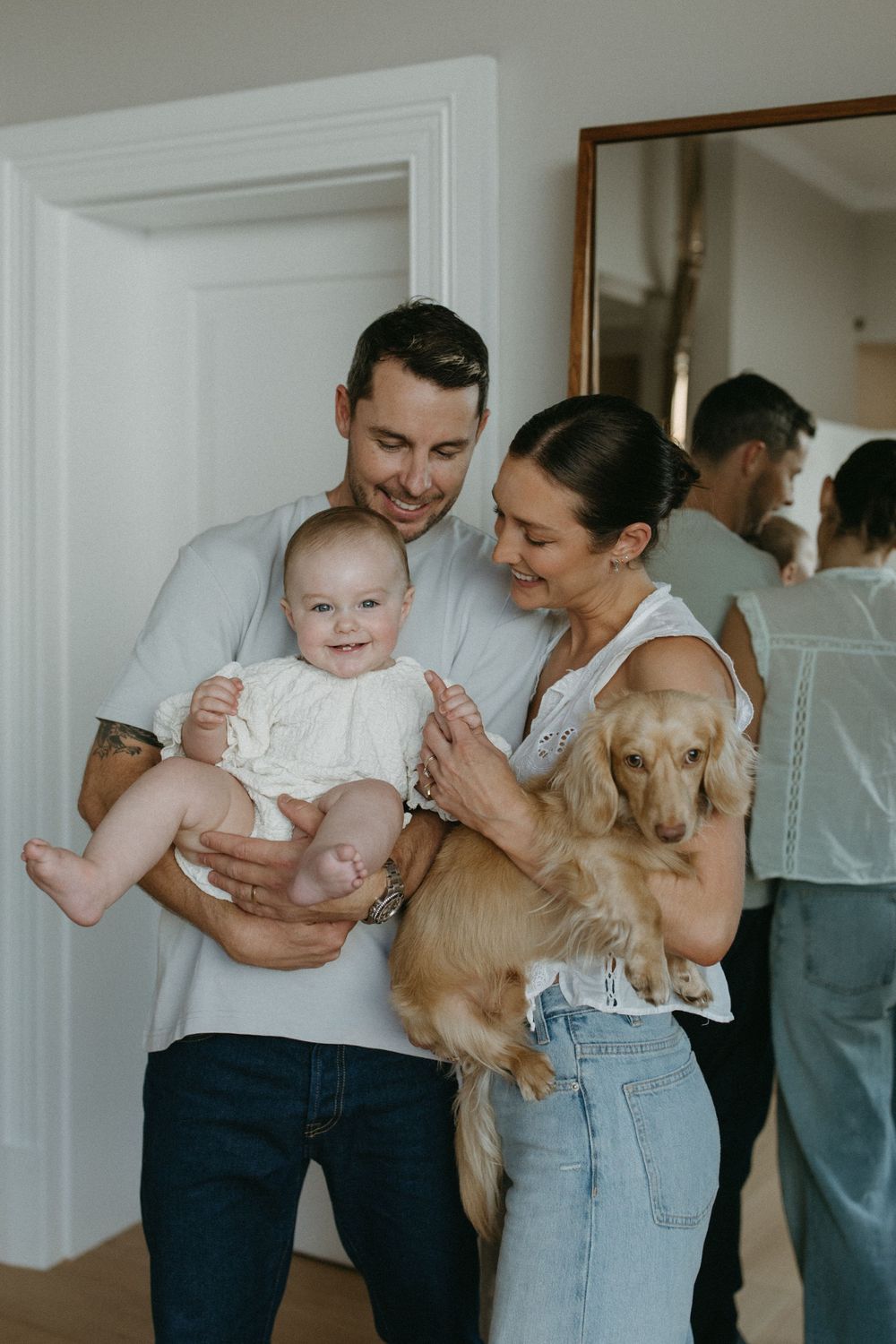 A series of four candid lifestyle photos showing tender moments between parents and baby with a golden retriever dog.