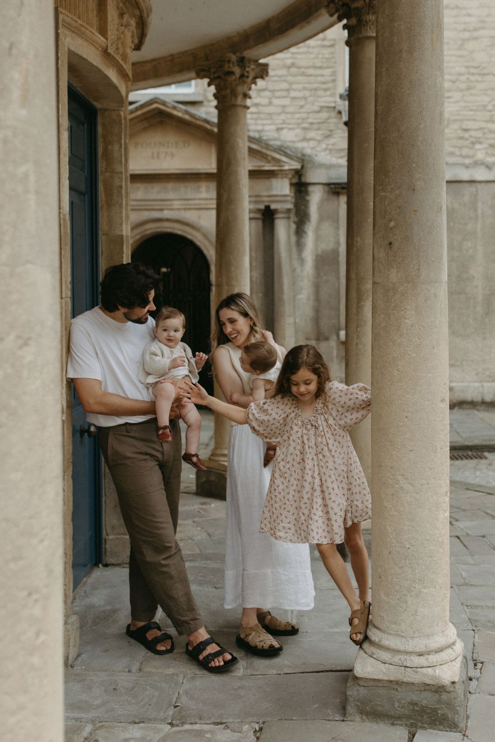 Family playing and posing between classic stone columns in an elegant architectural setting.
