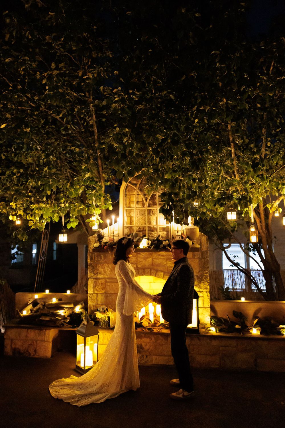 A couple stands in silhouette against illuminated garden archway during evening ceremony.