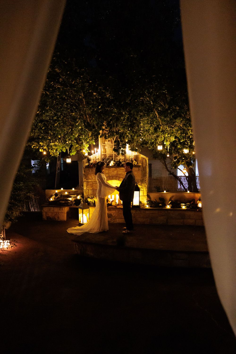 Romantic nighttime garden wedding scene with lanterns and candlelight.