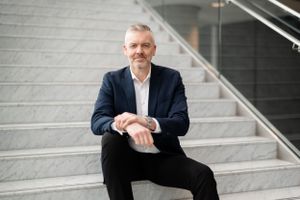 Professional business person in navy blazer seated on modern grey steps in an office building.