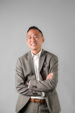 Professional headshot series showing expressions in a gray suit and white shirt against a light background.