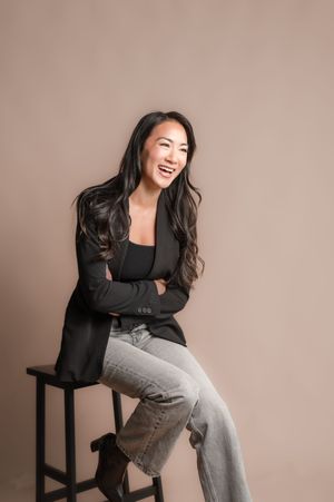 A series of casual studio portraits showing someone seated on a stool wearing a black blazer and grey pants.