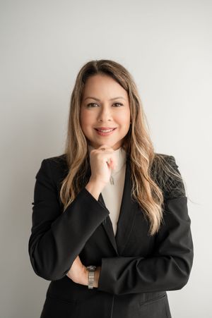 Professional portrait of someone wearing a black blazer against white background with warm expression.