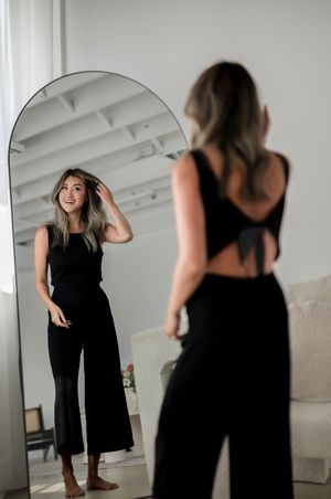 Series of photos showing person in black dress dancing and twirling in bright white studio space.