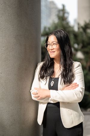 Professional portrait series showing a person in a black dress and cream blazer posing against a column backdrop.