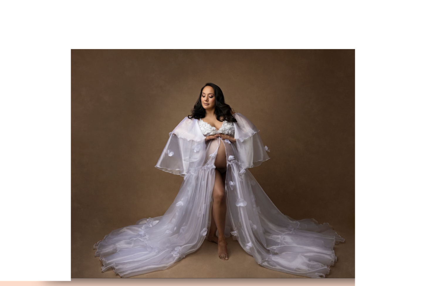Dramatic maternity portrait in flowing white cape dress with long train.