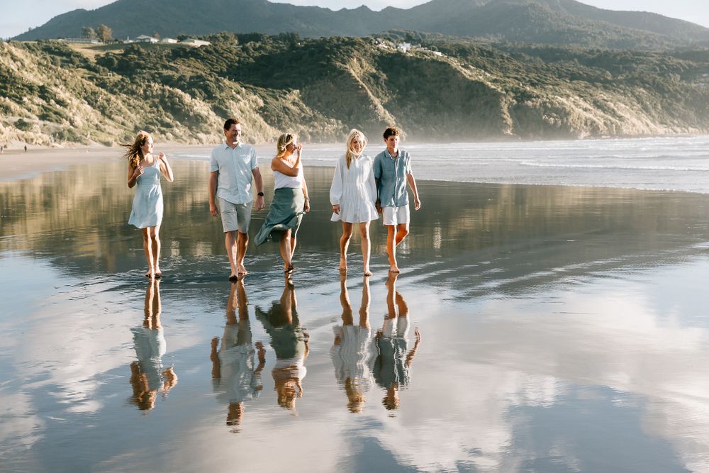 family photo walking in water on the beach