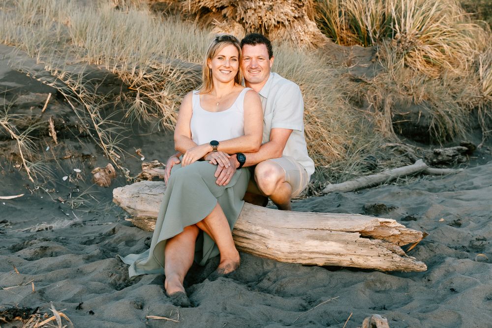 mum and dad photo on a log at a beach