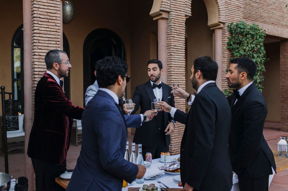 A group gathers for drinks at an elegant outdoor terrace with brick arches and columns.