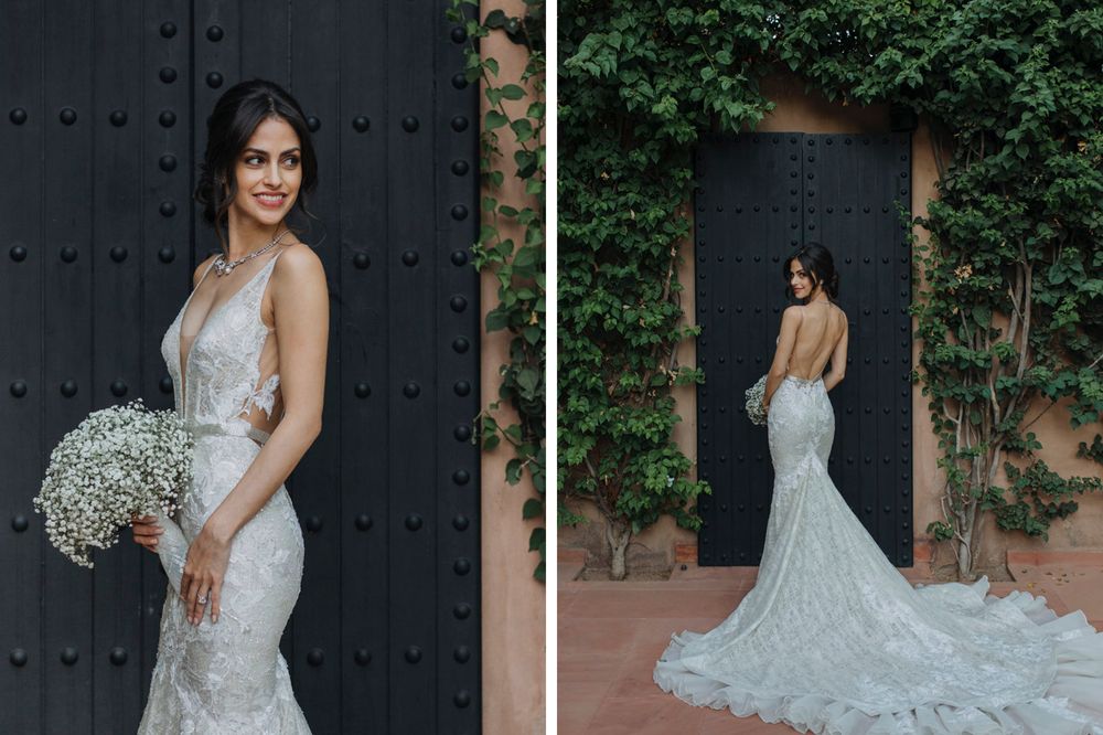 A stunning lace wedding dress with a flowing train photographed against a dark wooden door and ivy wall.